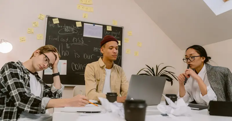 Young diverse coworkers brainstorming ideas in an office with a chalkboard.