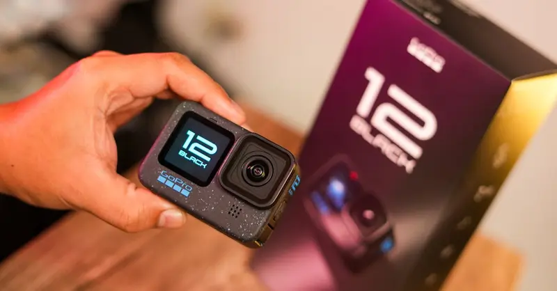 Close-up of a person holding an action camera with packaging box in the background.