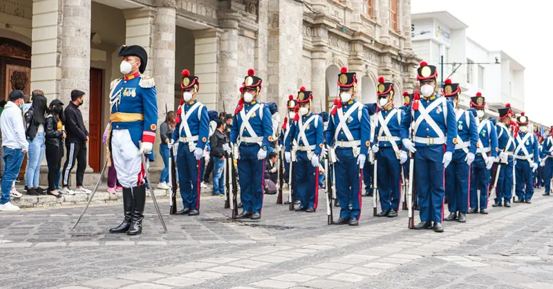 Ecuadorian soldiers in ceremonial uniforms stand in formation during a parade, showcasing tradition and discipline.