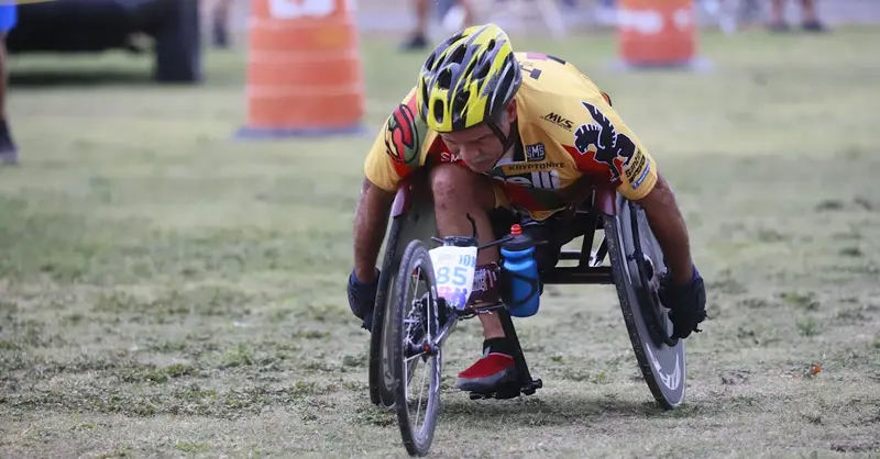 Determined wheelchair racer competing in an outdoor marathon, displaying focus and athleticism.