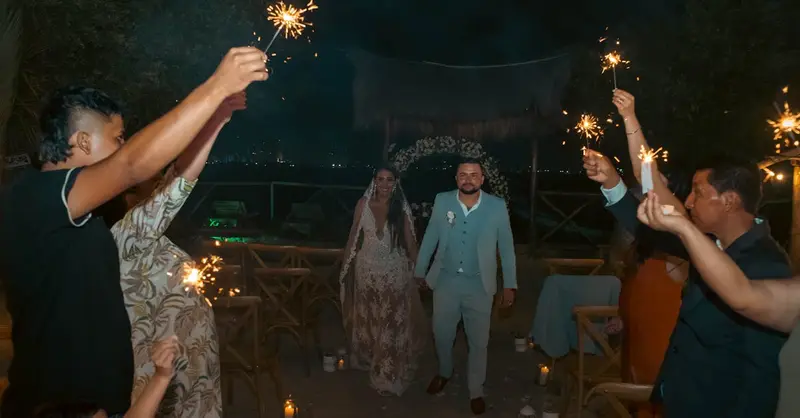 A couple's outdoor wedding ceremony with guests holding sparklers creating a festive atmosphere.