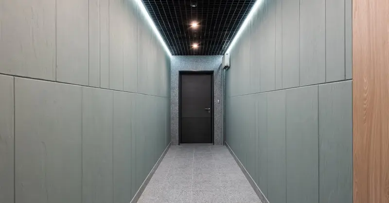 Perspective view of empty hallway with entrance door and illuminated ceiling in contemporary workplace