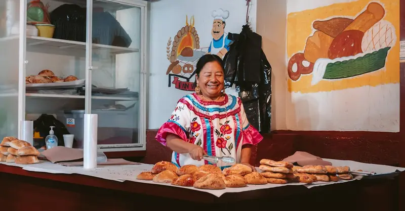 A woman in traditional dress sells freshly baked bread at a bakery in Oaxaca.