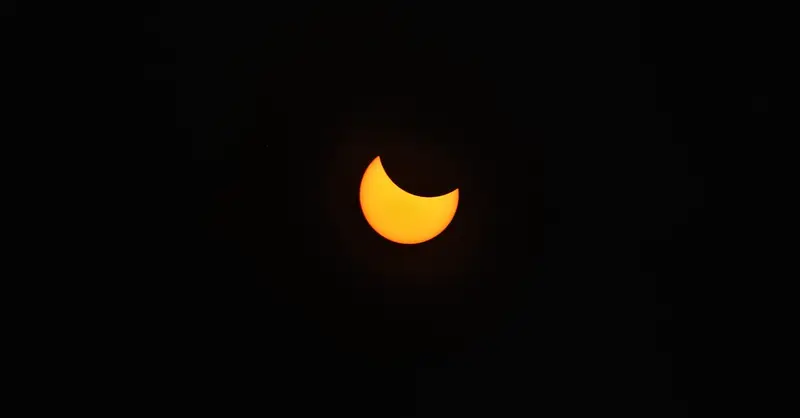 A stunning view of a partial solar eclipse captured against a pitch-black sky.