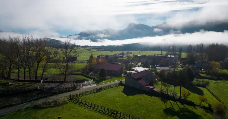 Scenic view of a misty rural landscape in Riaño, Spain with mountains and farms.