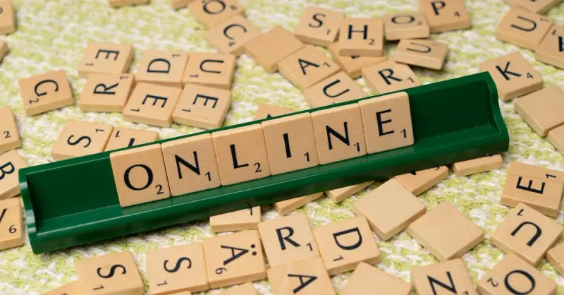 Scrabble tiles spelling 'online' on a green tray amidst scattered tiles, symbolizing digital connectivity and language.