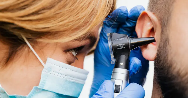 Close-up of a doctor performing an ear examination with an otoscope.