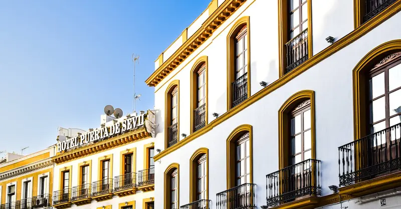 Elegant architectural facade of Hotel Puerta de Sevilla bathed in sunlight, capturing its iconic charm.