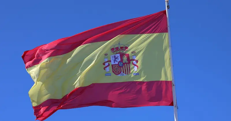 Vibrant Spanish flag waving in Cádiz, Spain, set against a bright blue sky.