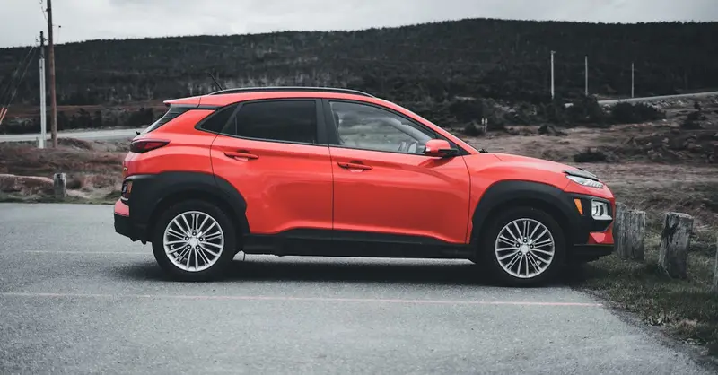 Red SUV parked outdoors on a cloudy day, showcasing sleek design and vibrant color.