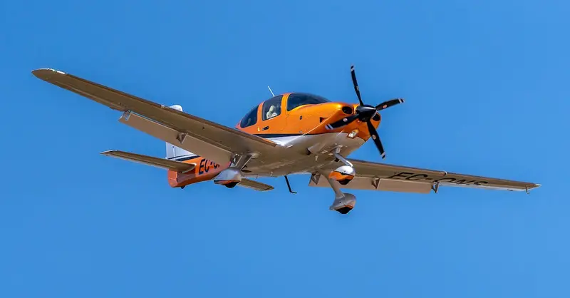 Close-up of a single-engine propeller airplane flying against a clear blue sky, showcasing aviation technology.