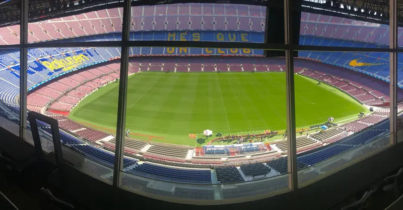 Wide view of Camp Nou stadium showcasing its vast seating and green pitch.