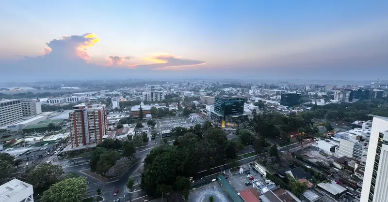Panoramic aerial view of Guatemala City during sunset, showcasing urban landscape and skyline.
