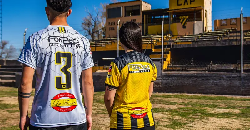 Two sports fans wearing team jerseys at the CAP stadium on a sunny day.