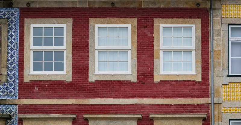 Vibrant red brick facade with traditional Portuguese white windows in Porto, Portugal.