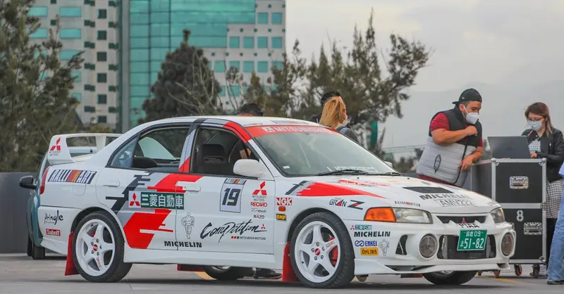 Modified Mitsubishi rally car parked outdoors with people nearby.