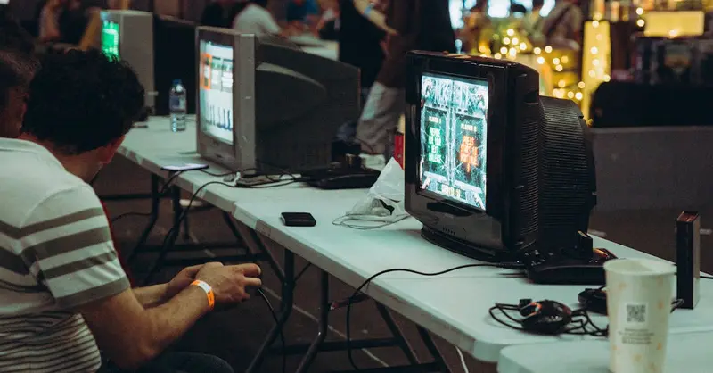 Adults enjoying a retro gaming event with CRT televisions and consoles, creating a nostalgic atmosphere indoors.