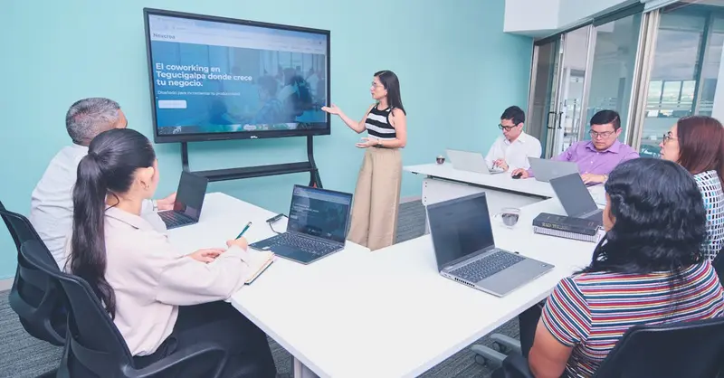 A diverse group in a collaborative meeting using a digital display in a modern office.