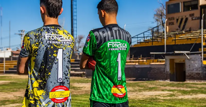 Two young soccer players in colorful jerseys, ready for a match on an urban field.