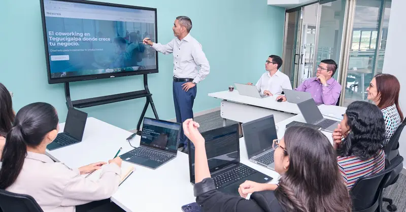 Professional team engaged in a business presentation with laptops and a projector screen.