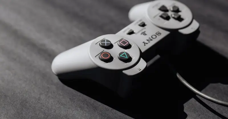 Retro Sony game controller with classic buttons on a textured dark surface, showcasing vintage electronics.