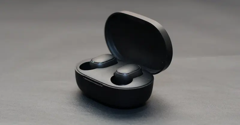 Modern wireless earbuds in an open black charging case on a matte surface.