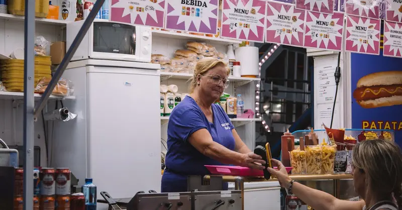 Woman buying food at street stall in Valencia, Spain, highlighting local cuisine and culture.