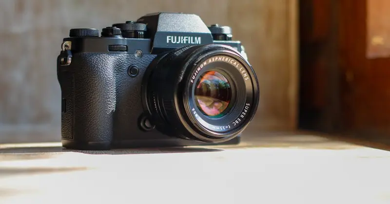 A detailed photo of a classic Fujifilm camera on a sunlit wooden table.