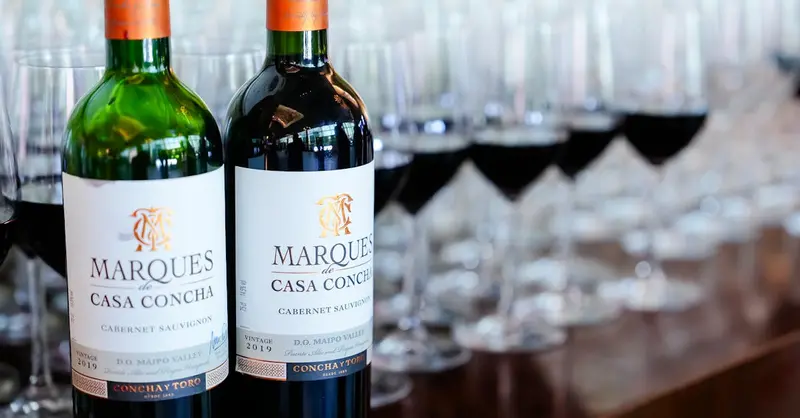 Close-up of Marques de Casa Concha wine bottles with filled wineglasses in a table setting.