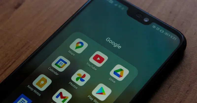 Close-up of a smartphone showing various Google apps on its screen.