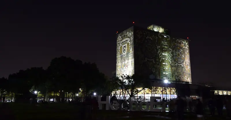 Illuminated facade of the UNAM Central Library at night in Mexico City, a UNESCO World Heritage Site.
