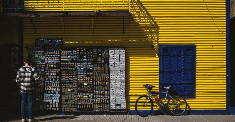 Vibrant yellow and blue facade in La Boca, Buenos Aires featuring a man and a bicycle.