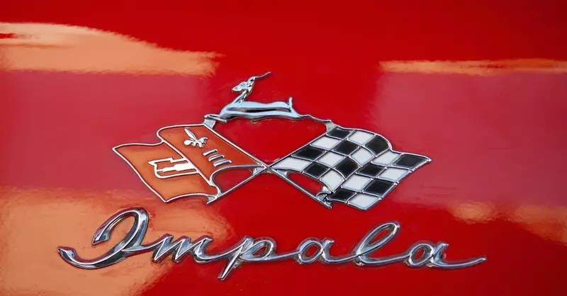 Close-up of a vintage red Chevrolet Impala emblem and logo.