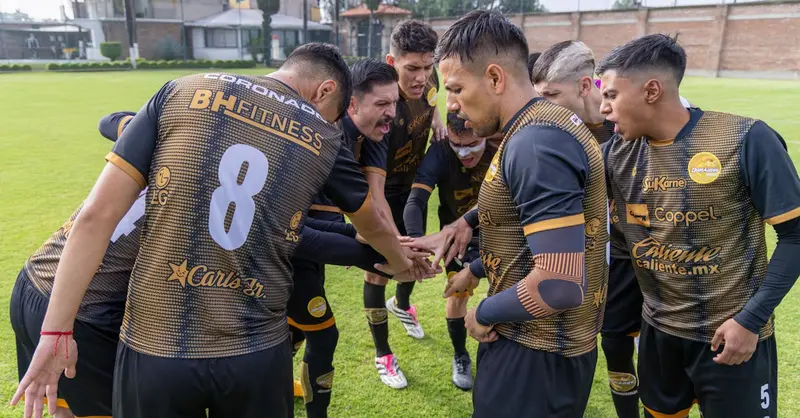 Soccer players in a team huddle on a sunny day at Texcoco, México, displaying unity and teamwork.