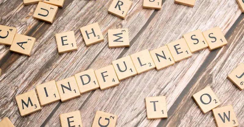 Wooden letter tiles spelling 'mindfulness' on a rustic wood background.
