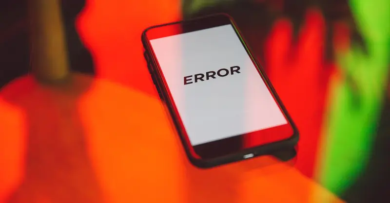 A smartphone displaying an 'ERROR' message surrounded by vibrant red and green reflections indoors.