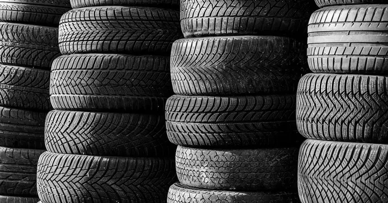 Black and white image of stacked vehicle tires showcasing various tread patterns.