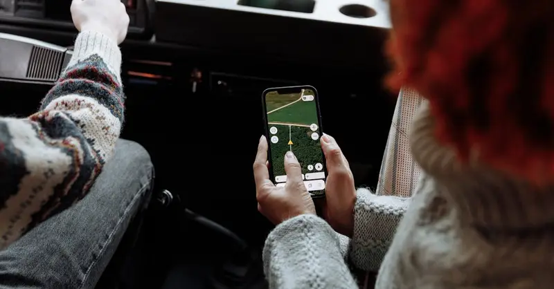 Two people using a navigation app on a smartphone during a road trip