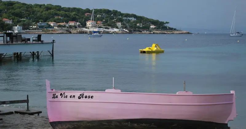 A charming pink boat titled 'La Vie en Rose' on a serene Antibes beach.