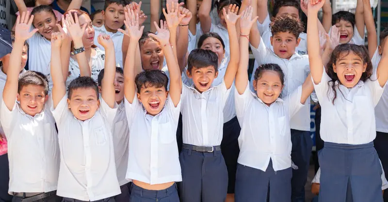 Joyful group of school children in Santa Rosa de Lima, El Salvador cheering outdoors.