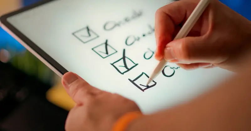 Close-up of a digital checklist being marked off on a tablet with a stylus pen.