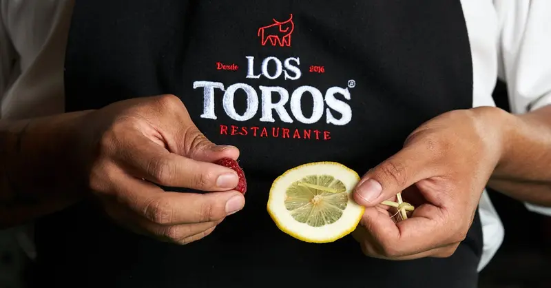 Close-up of chef holding lemon and garnish at Los Toros Restaurante.