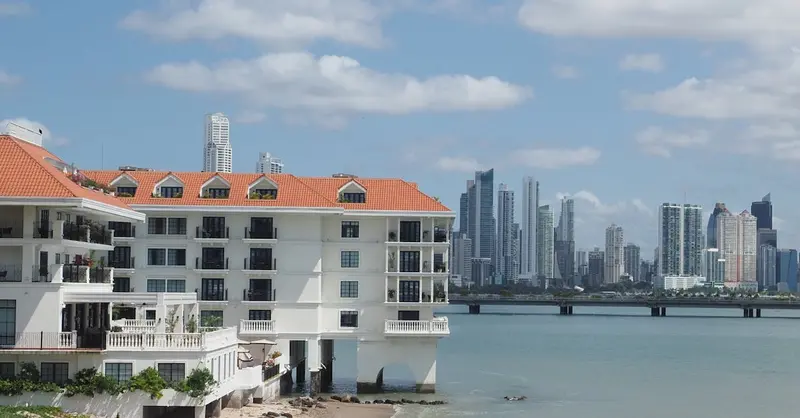 Panama City's skyline and a coastal building create a stunning view under a bright sky.
