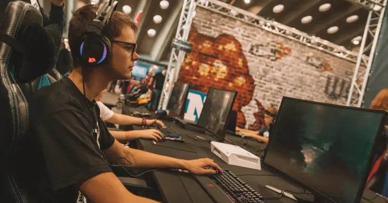 A young male gamer intensely focused during an esports event at an indoor gaming convention.
