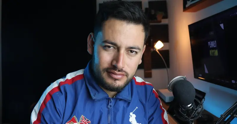 Close-up of a man in a home studio with microphone and computer setup.