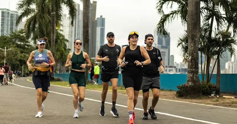 A group of diverse runners jogging along a scenic city pathway in Panama City, promoting healthy lifestyle.