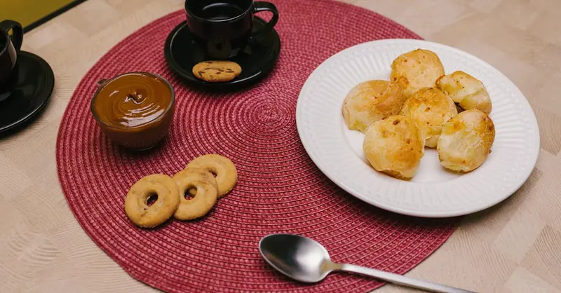 Delicious Brazilian snacks including pão de queijo, coffee, and cookies on a table.