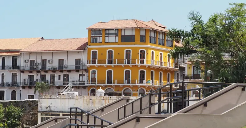 Vibrant yellow colonial building in Panama City against a clear blue sky, showcasing rich architectural details.