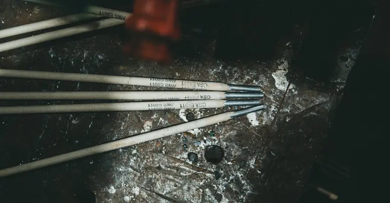 Close-up of welding electrodes on a rugged metal surface, showcasing industrial tools.