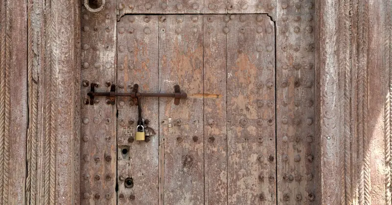 Detailed view of an ancient locked wooden door in Taza, Morocco, showcasing intricate craftsmanship.